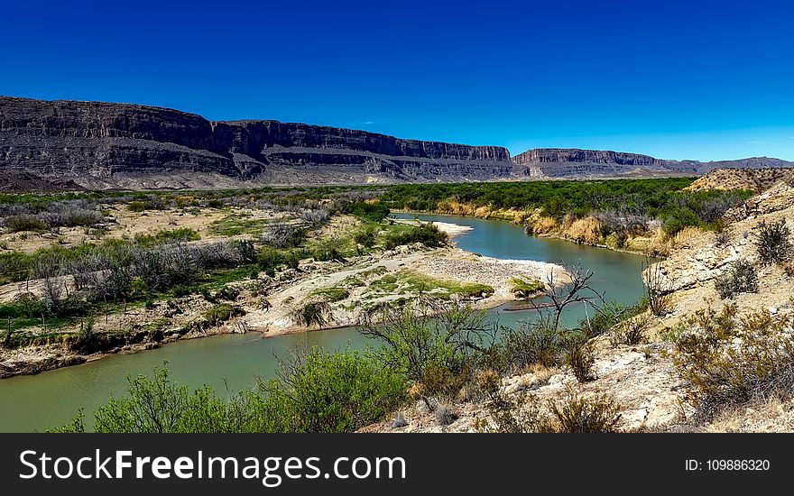 Body Of Water Between 2 Mountains Under Clear Sky During Daytime