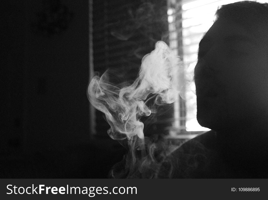 Gray Scale Photo of Human Smoking Inside the Room