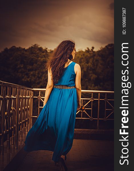 Woman Facing Away Wearing Blue Tank Long Dress Looking Out To Trees