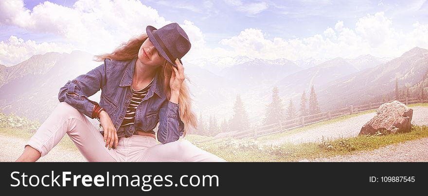 Woman Wearing Black Fedora Hat, Blue Denim Blazer and White Skinny Jeans While Sitting on Ground