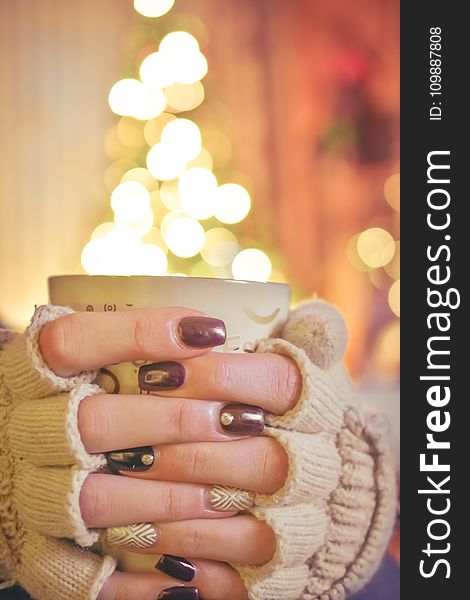 Person Holding a Mug Infront of a Lighted Christmas Tree