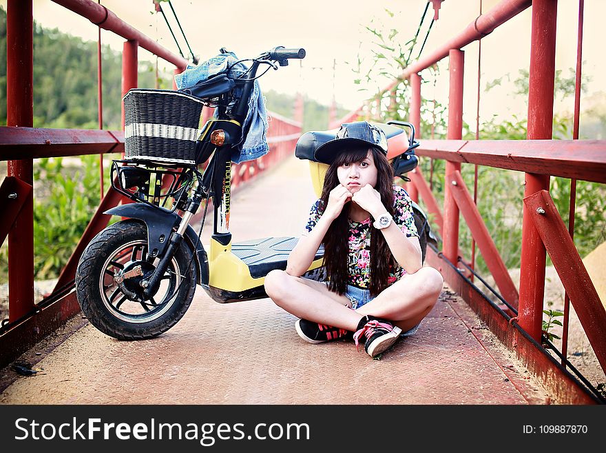 Woman Sitting On Bridge With Motor Scooter