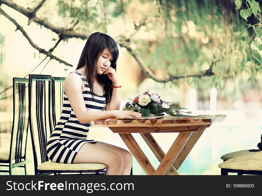 Woman Wearing Stripe Tank Bodycon Dress Sitting on Chair Leaning on Table
