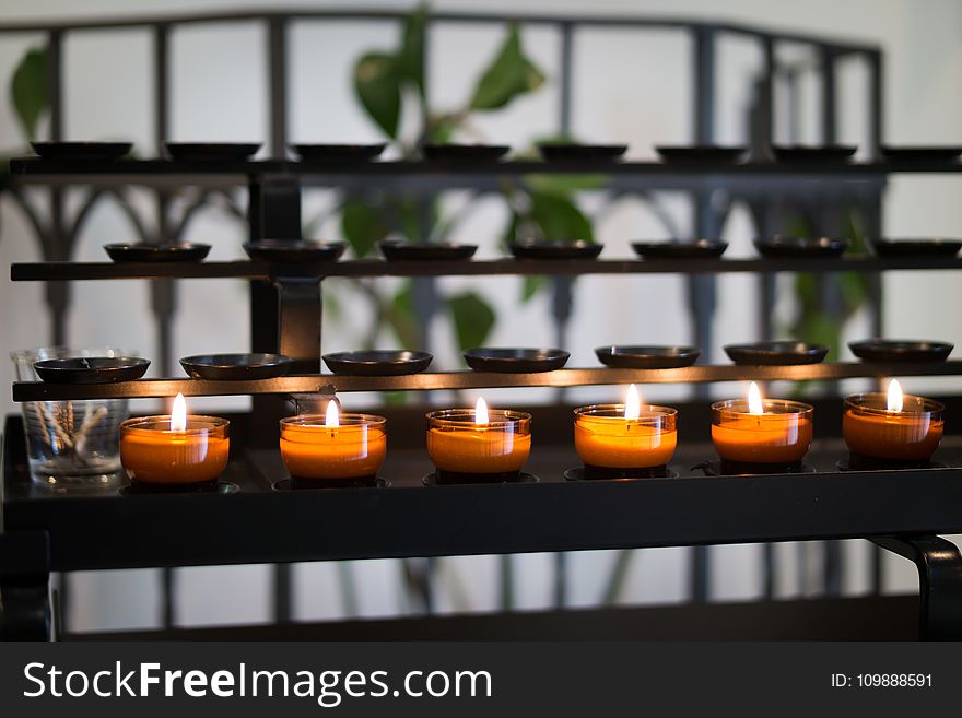 Close Up Photography of Tealight Candles on Black Metal Rack