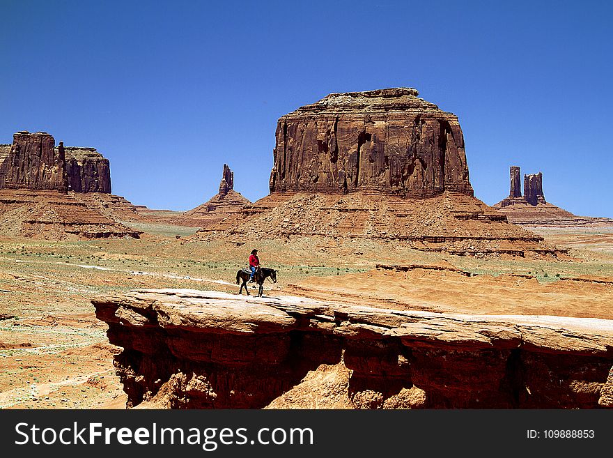 Person On Black Horse On Rock Cliff