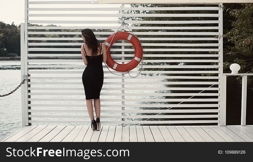 Woman in Black Sheath Dress Beside Swim Ring on Dock