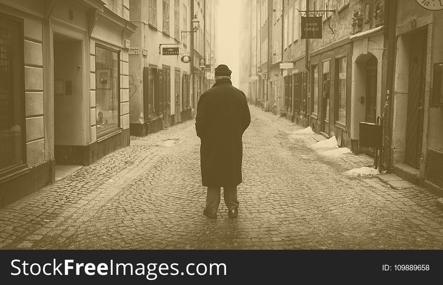 Rear View of a Man Walking on Cobblestone