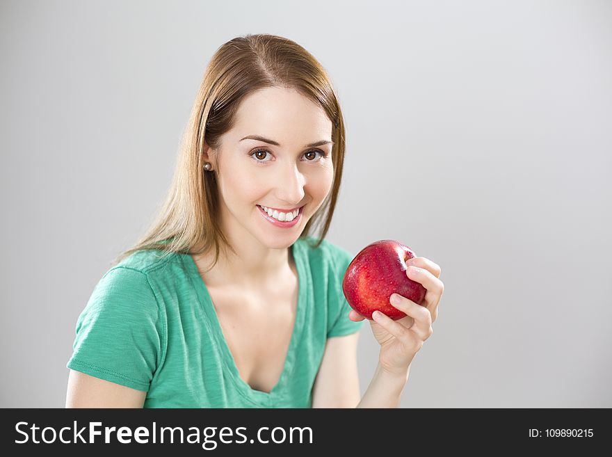 Portrait of Young Woman Eating Fruit Against White Background
