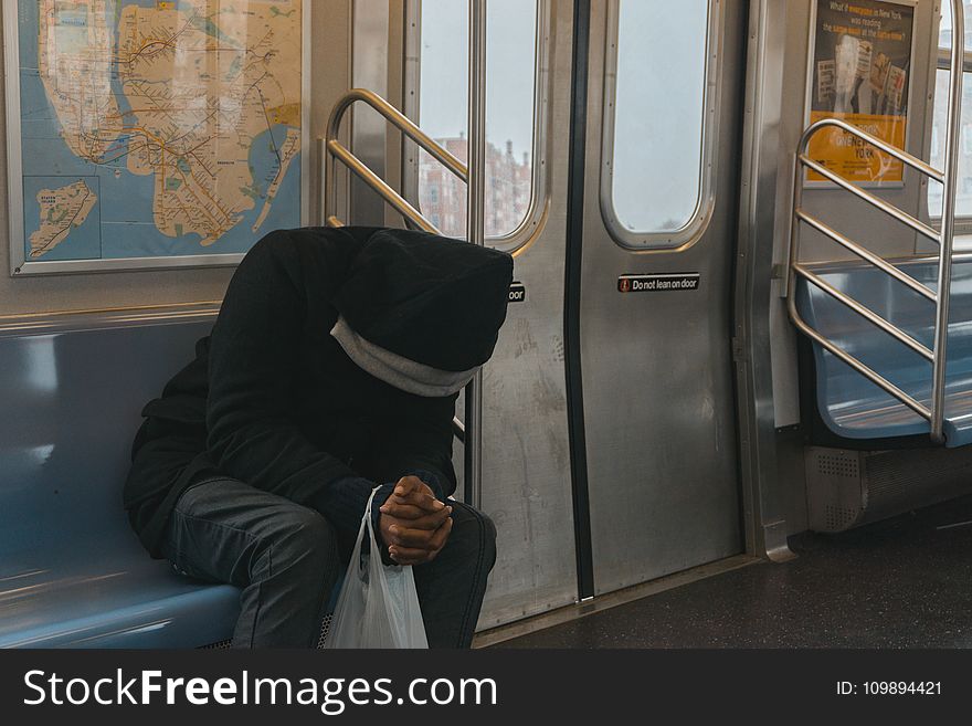 Person in Black Hoodie Sitting on Train Bench