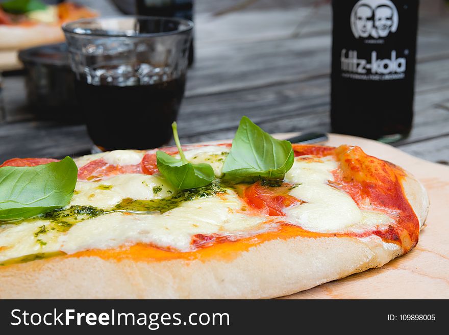 Pizza Top With Green Leafy Vegetable Near Glass Of Black Liquid