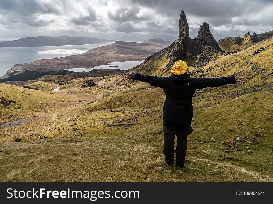 Person Wearing Black Jacket Standing on Green Grass Field Near Lake