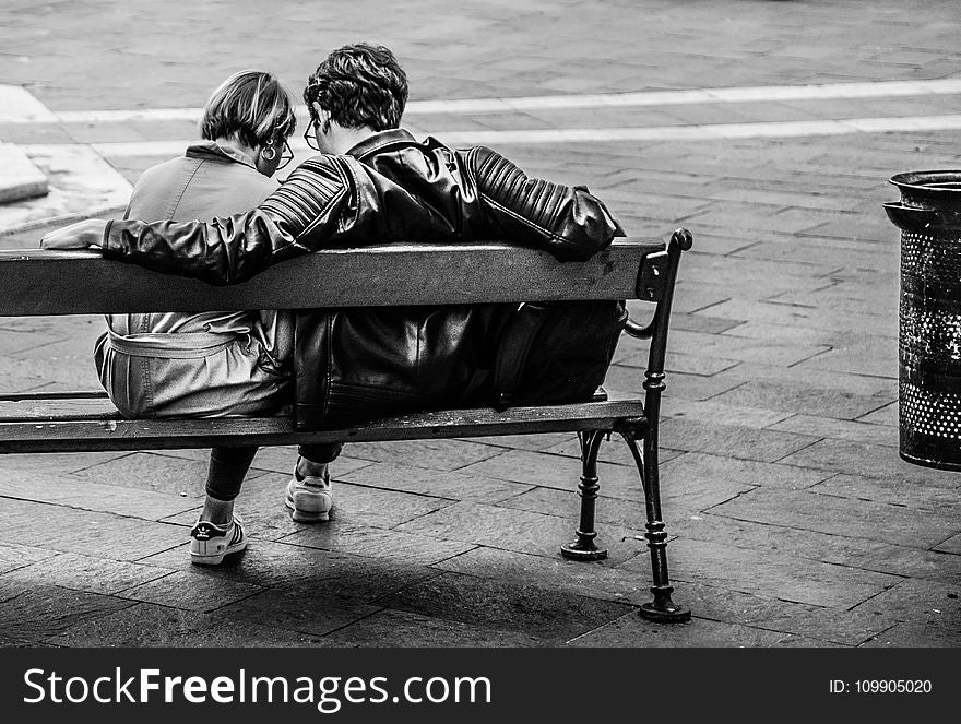 Grayscale Photo of Two Person Sitting on a Bench