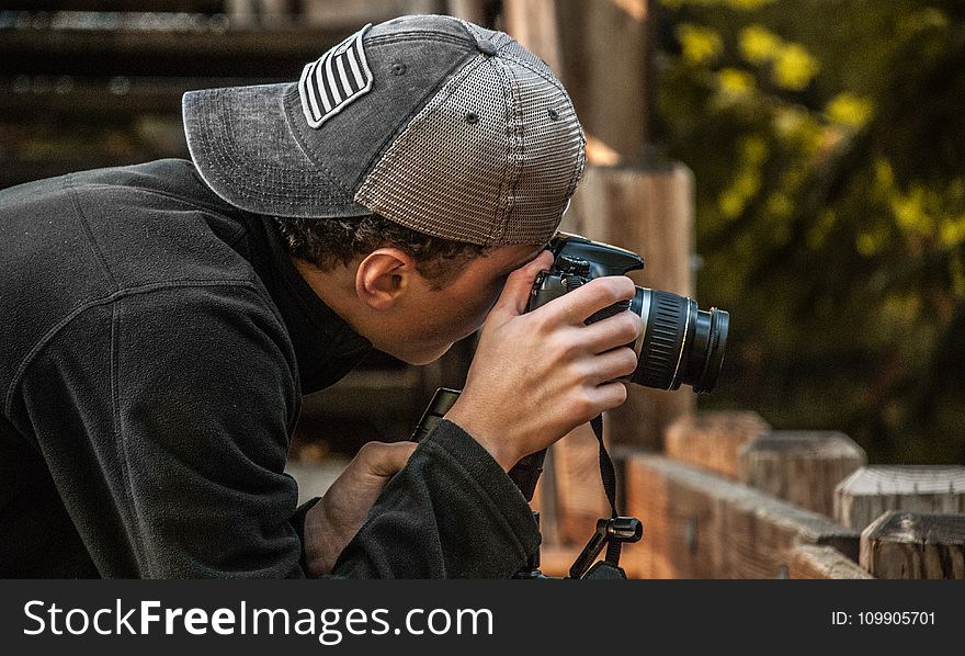 Depth of Field Photography of Man Holding Dslr Camera