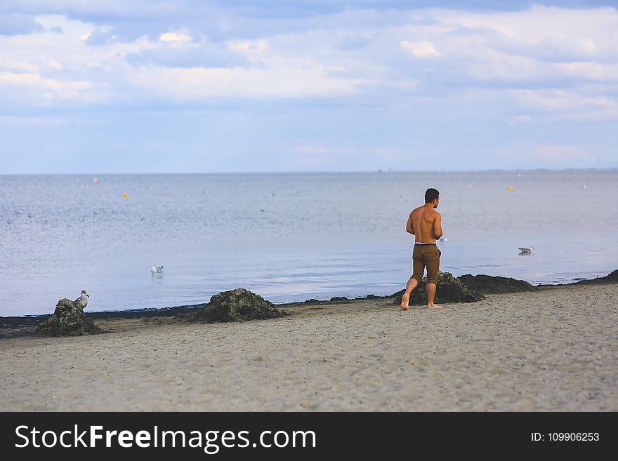 Young man walking on sand beach