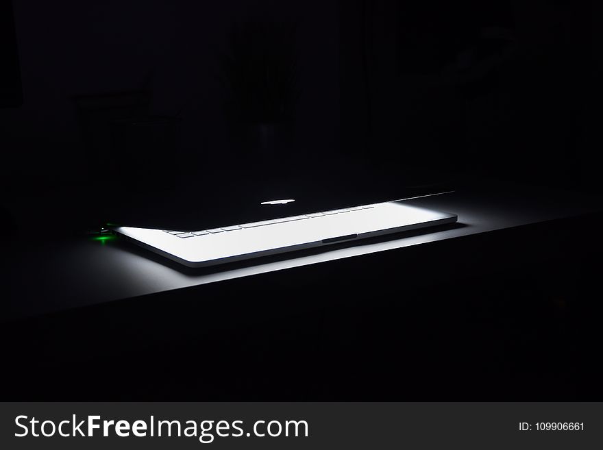 Photography of Macbook Half Opened on White Wooden Surface