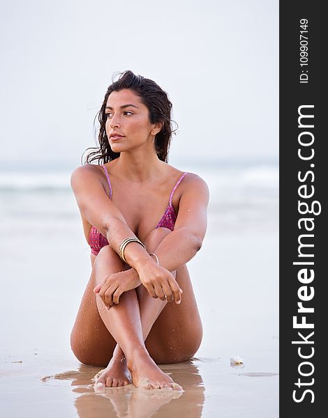 Woman in Purple Bikini Sitting on Shore