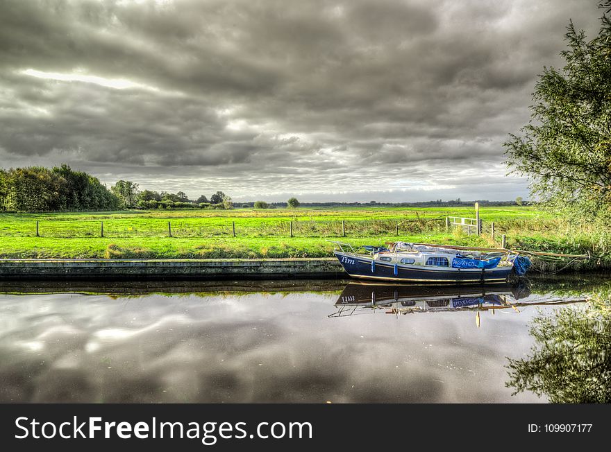 White and Blue Power Boat on Body of Water Under Clouds