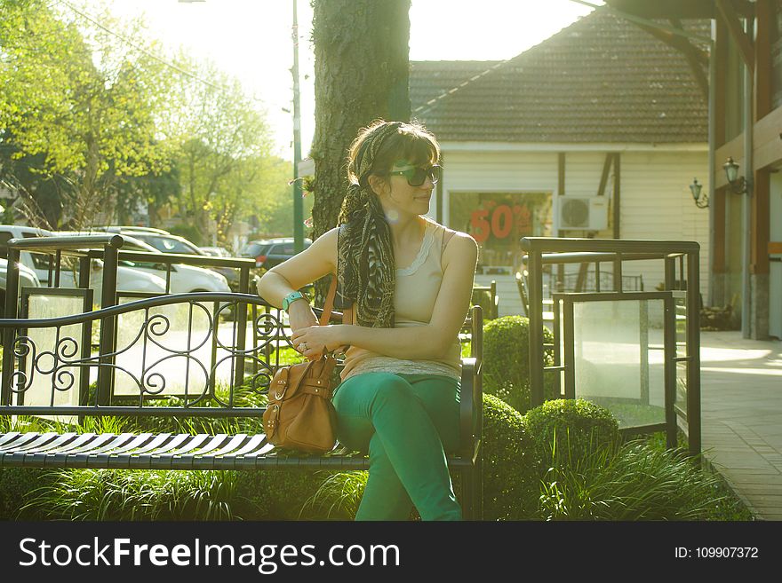 Woman in Brown Tank Top Sitting on Black Bench Beside Tree