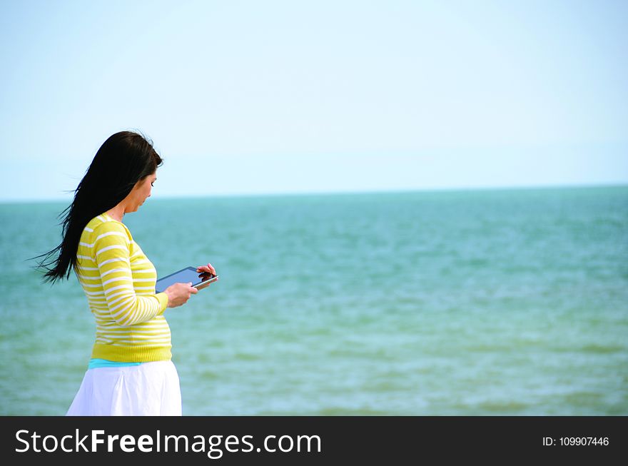 Woman In Yellow Long Sleeved Shirt And White Skirt Walking On Seashore