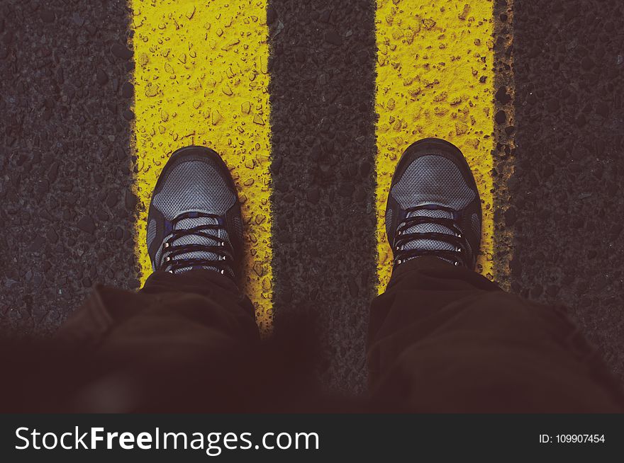 Person in Gray Sneakers Standing on Pedestrian Lane