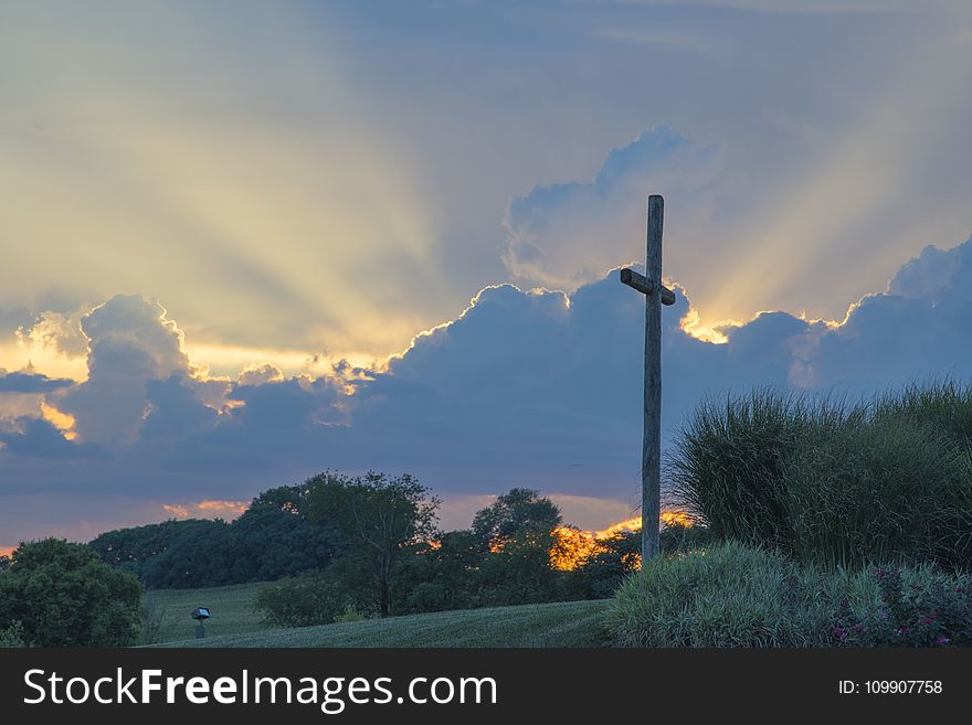 Big Wooden Cross On Green Grass Field Under The White Clouds