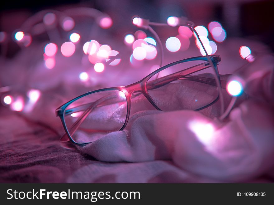 Shallow Focus Photography of Blue-framed Eyeglasses Near String Lights