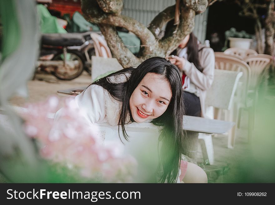 Selective Focus Photography of Woman Sitting on Chair Near Tree Branch
