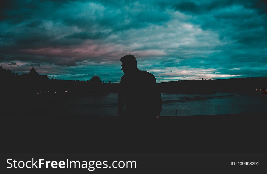 Man Silhouette Near Body of Water at Nighttime