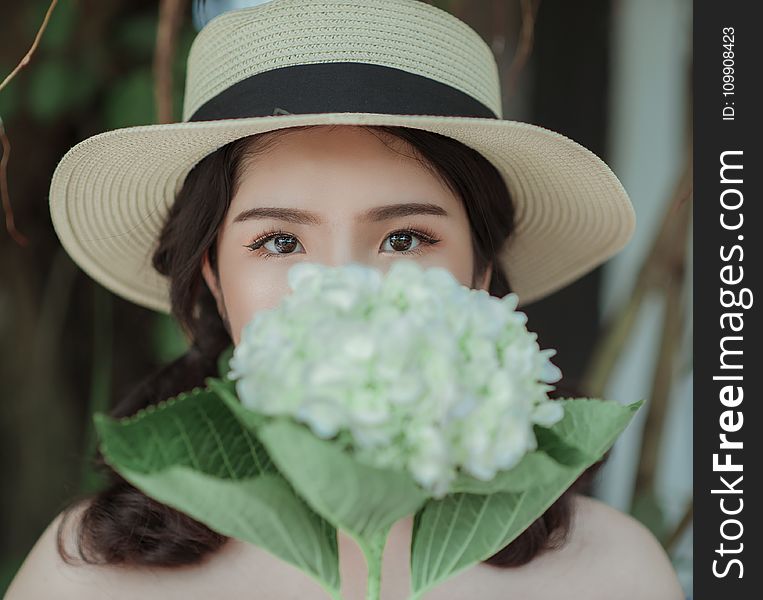Woman Wearing White Hat Holding Flowers