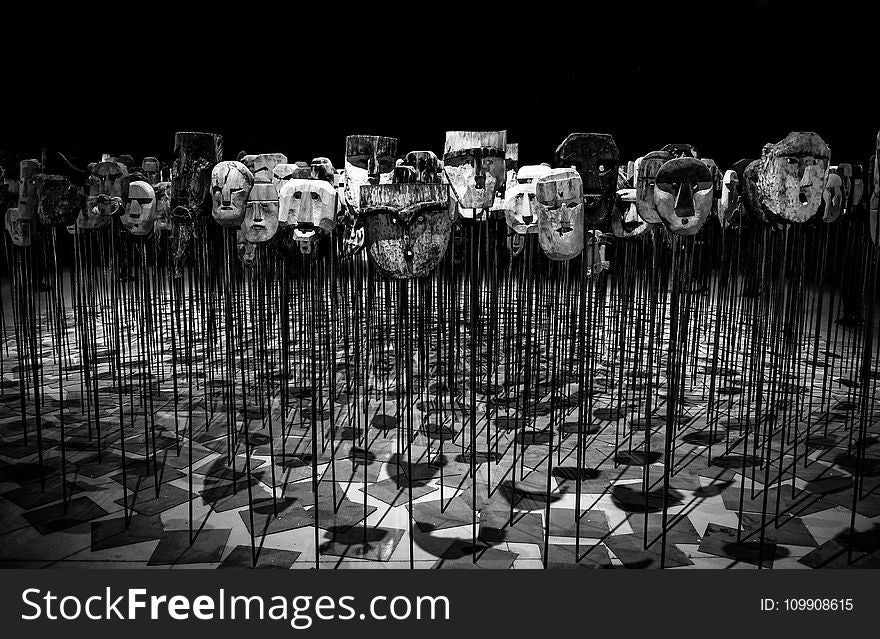 Greyscale Photo of Masks on a Stick