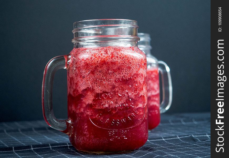 Closeup Photography Of Two Clear Glass Jar Filled With Red Liquid On Top Of Blue And White Tattersal Textile