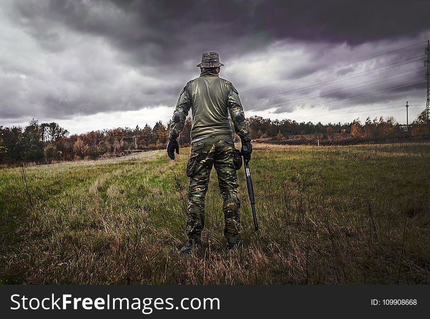 Man in Camouflage Suit Holding Shotgun