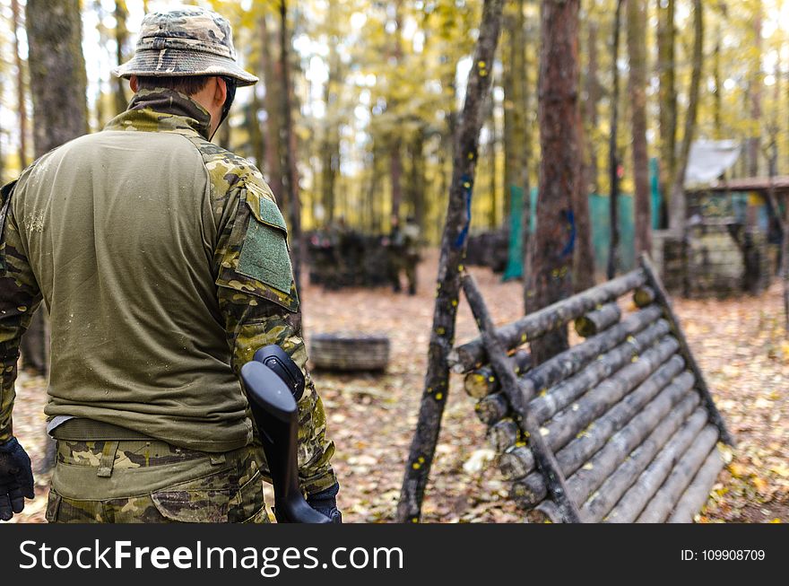 Selective Focus Photography Of Man Wearing Camoflouge Suit While Holding A Gun