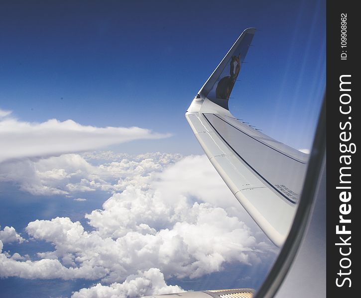 High-angle Photograph of Airplane Wings Above the Clouds Under Clear Blue Sky