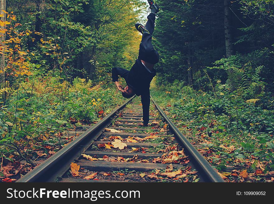 Man Standing With His Right Hand on the Train Rails in Middle of Forest