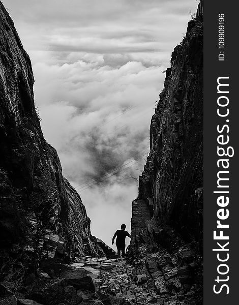 Silhouette of Man Walking Between Two Cliff