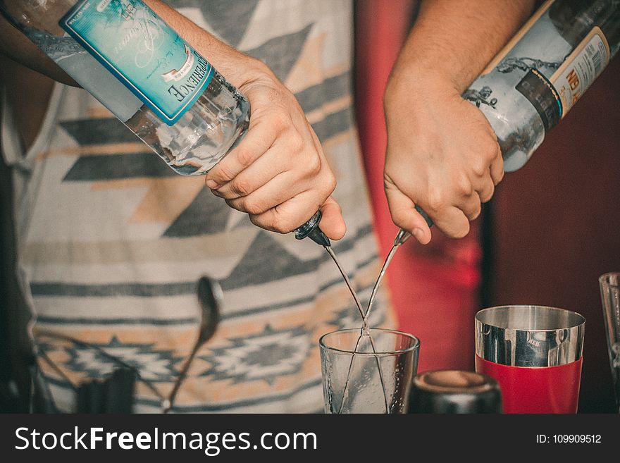 Person Holding Two Soda Bottles With Drinking Glass Below