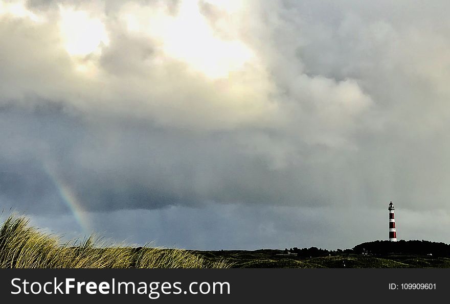 White And Red Lighthouse On Far Right And Rainbow On Far Left