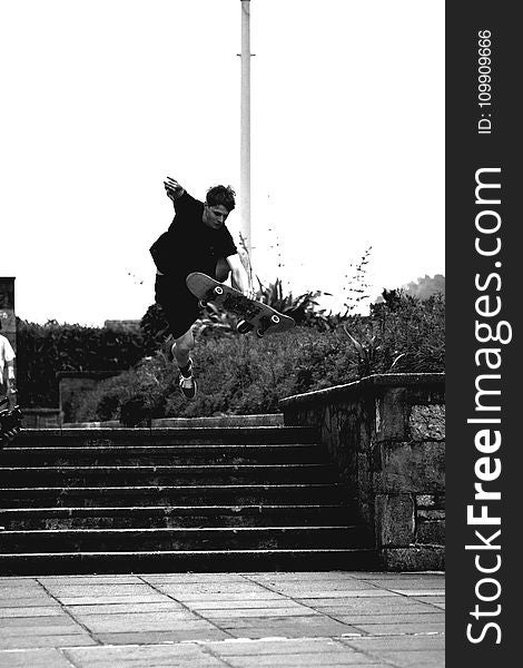 Grayscale Photo of Man Doing Trick on Skateboard on Park