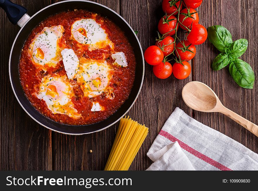Black Frying Pan With Spaghetti Sauce Near Brown Wooden Ladle and Ripe Tomatoes