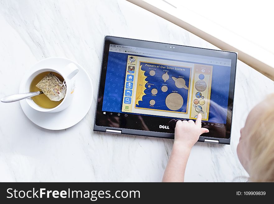 Kid Using Black Dell Tablet With Tea