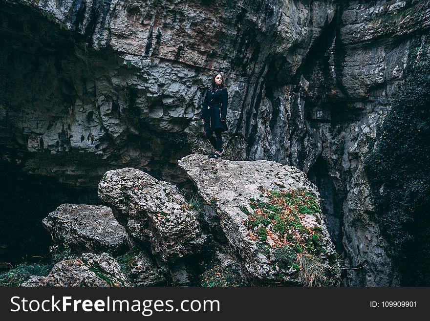 Photo of Woman In Black Outfit Standing On Rock