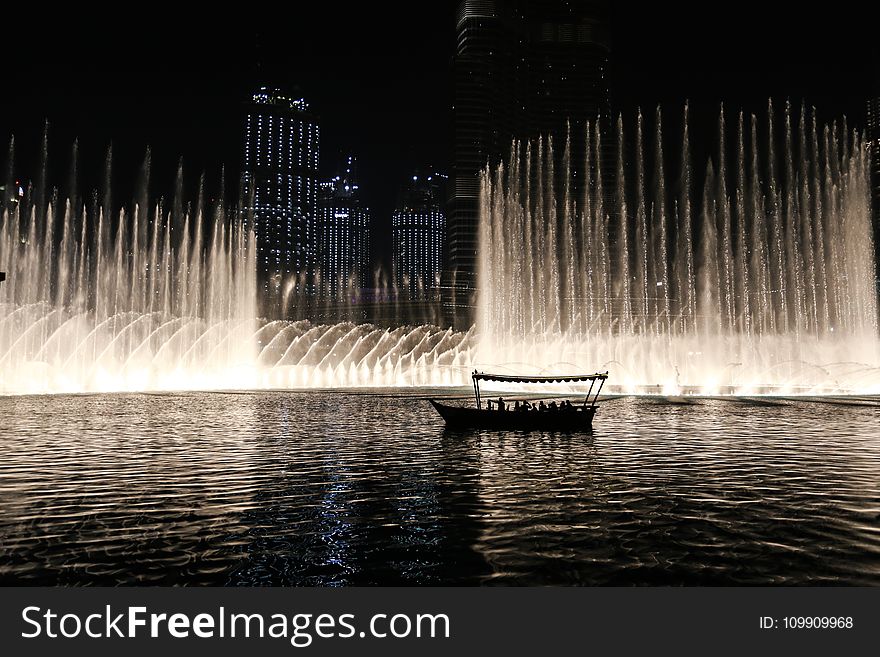 Silhouette Of A Boat On A Body Of Water With Fountain