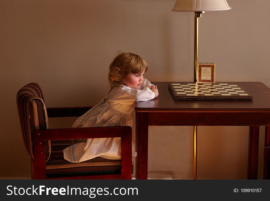 Child Setting on Chair in Front of Table