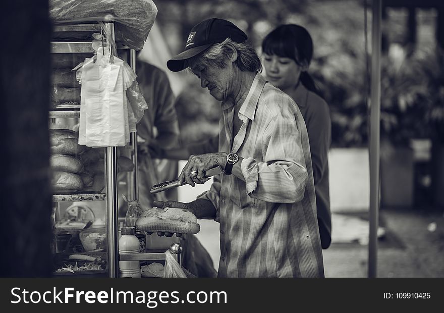 Man in Cap Holding a Pastry and Tong