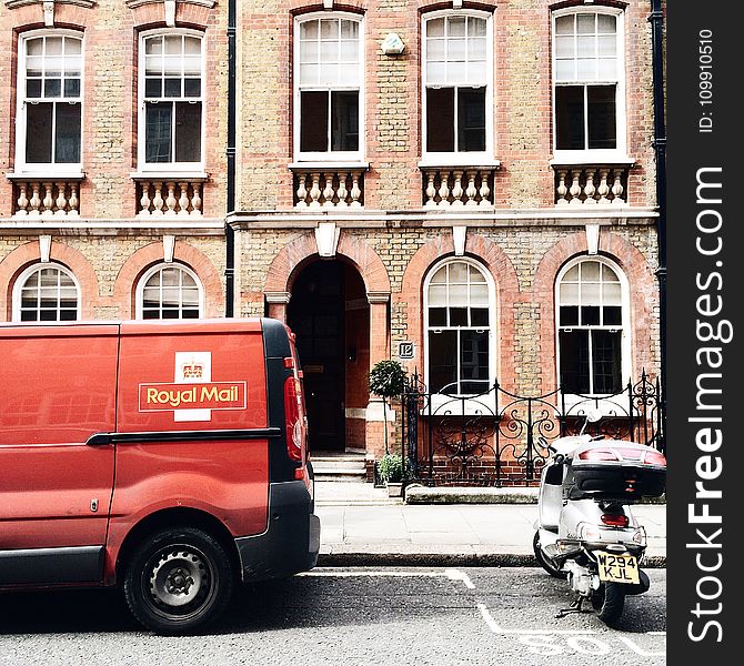 Red Royal Mail Parked Near Brown Brick Building