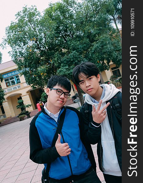 Man in Blue Hoodie Beside a Man in Black Jacket Standing Outdoors Under Blue and White Sunny Sky during Dayimte