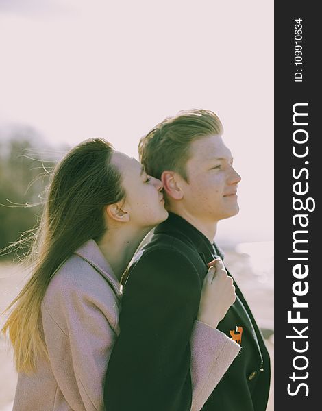 Woman Kissing the Back of Man&#x27;s Ear Near Sea