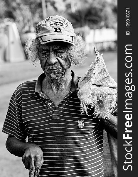 Grayscale Photography Of Man Wearing Polo Shirt And Holding Sack