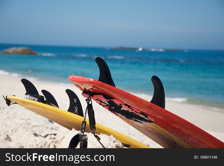 Yellow And Red Surfboards Near Blue Calm Body Of Water